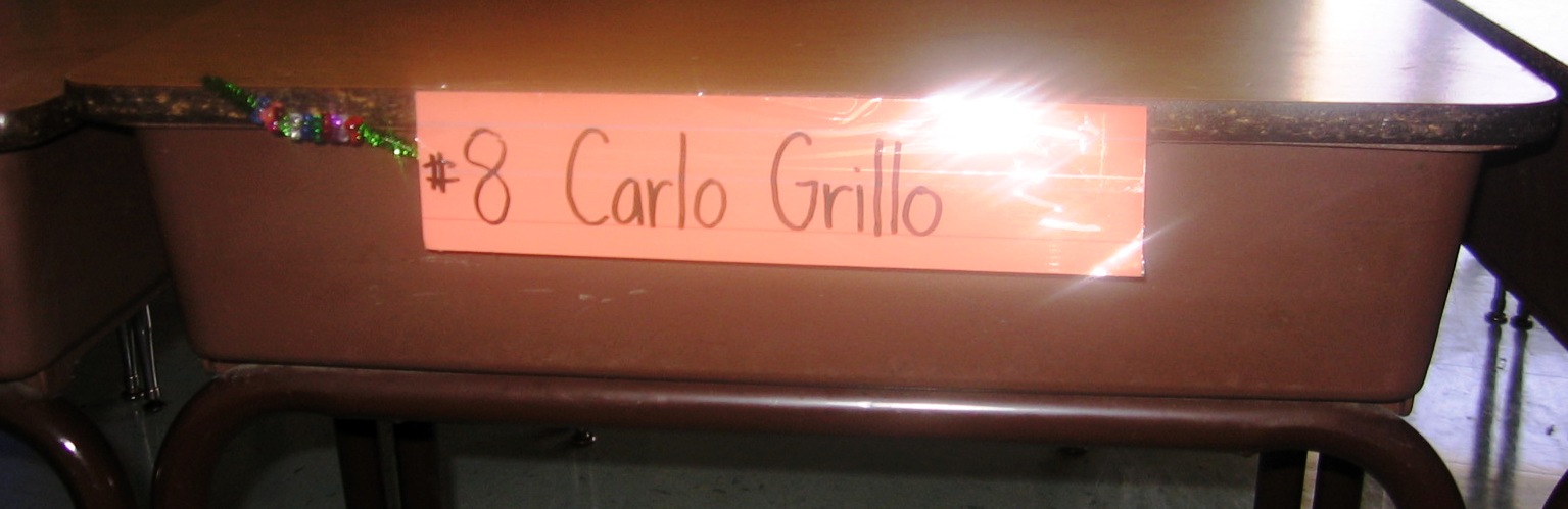 Initially, I taped each student’s pipe cleaner to his or her nametag, which hung off the front of the desks where they wouldn’t be touched (pictured above). When I moved the desks together, I couldn’t have the nametags hang off the front, so I put small nametags (post-it notes, in the photo to the right) on the upper-left corner of each desk and taped the pipe cleaner to it. In later years, I started tying the pipe cleaner to the back of their chairs so I didn’t have to use tape. I’ve found the chairs are the best place to attach the pipe cleaner.